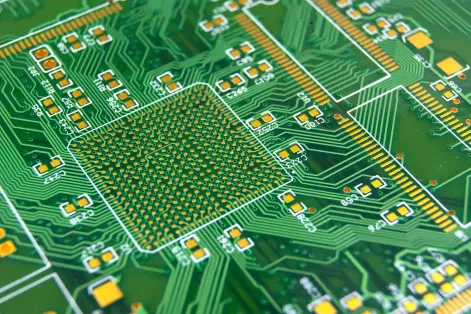 Close-up of PCB with green solder mask protecting copper traces and exposing pads.