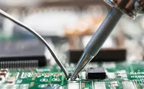 Hand soldering a through-hole component on an FR-4 PCB with a soldering iron