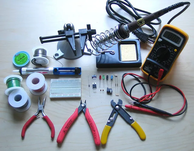 PCB repair tools including soldering iron and multimeter.
