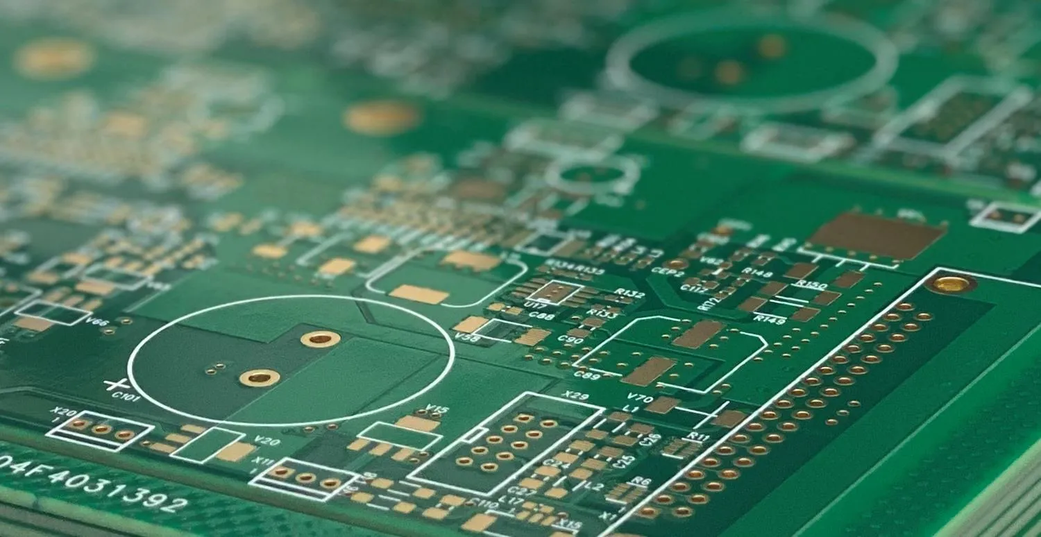 Close-up of PCB with green solder mask and exposed copper pads.