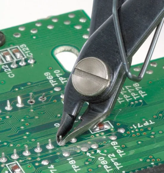 Flush cutters trimming leads on through-hole PCB components."