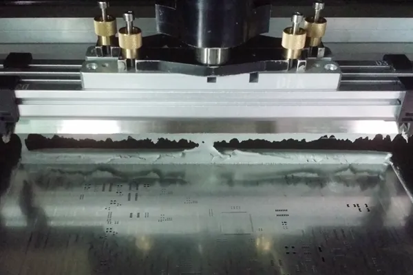 Applying solder paste to a PCB using a stencil for SMT assembly.