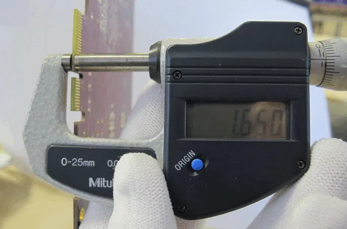 Measuring the thickness of a finished PCB with a caliper.