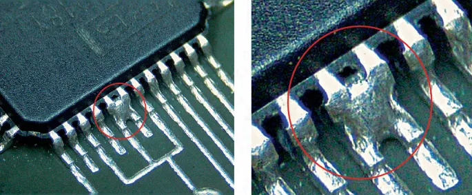 Close-up of a solder bridge on a PCB causing a short circuit.