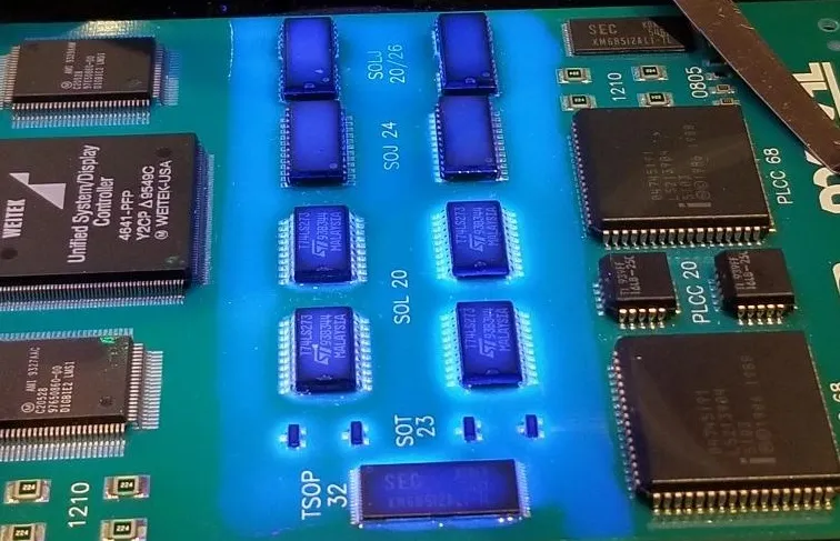 Inspecting PCB for flux residue under UV light.