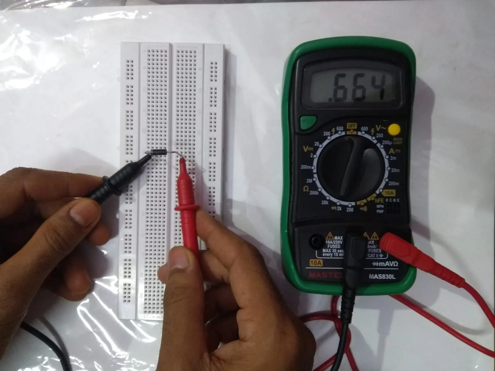 Component-level diagnostic on a PCB testing a capacitor with a multimeter."