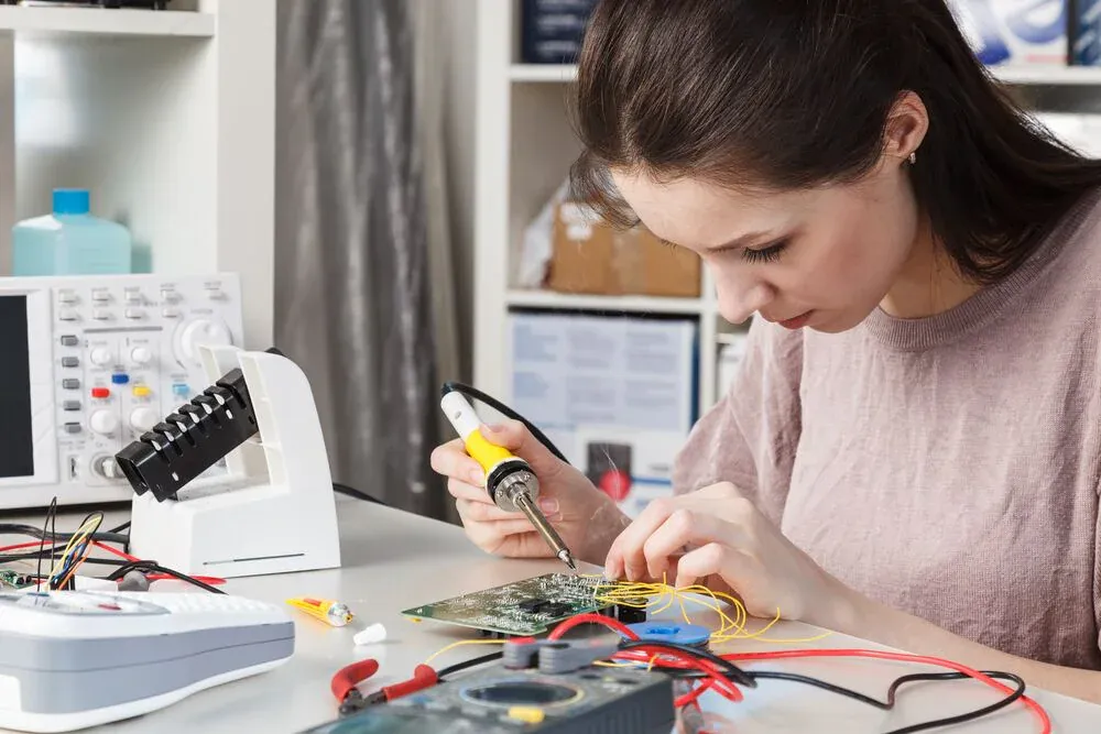 Hobbyist performing DIY PCB diagnostic with multimeter and tools."
